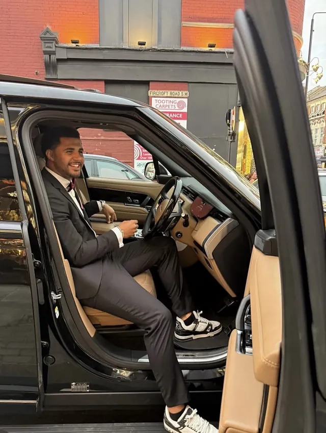 Tyson Isa smiling in a suit stepping into a car in London.